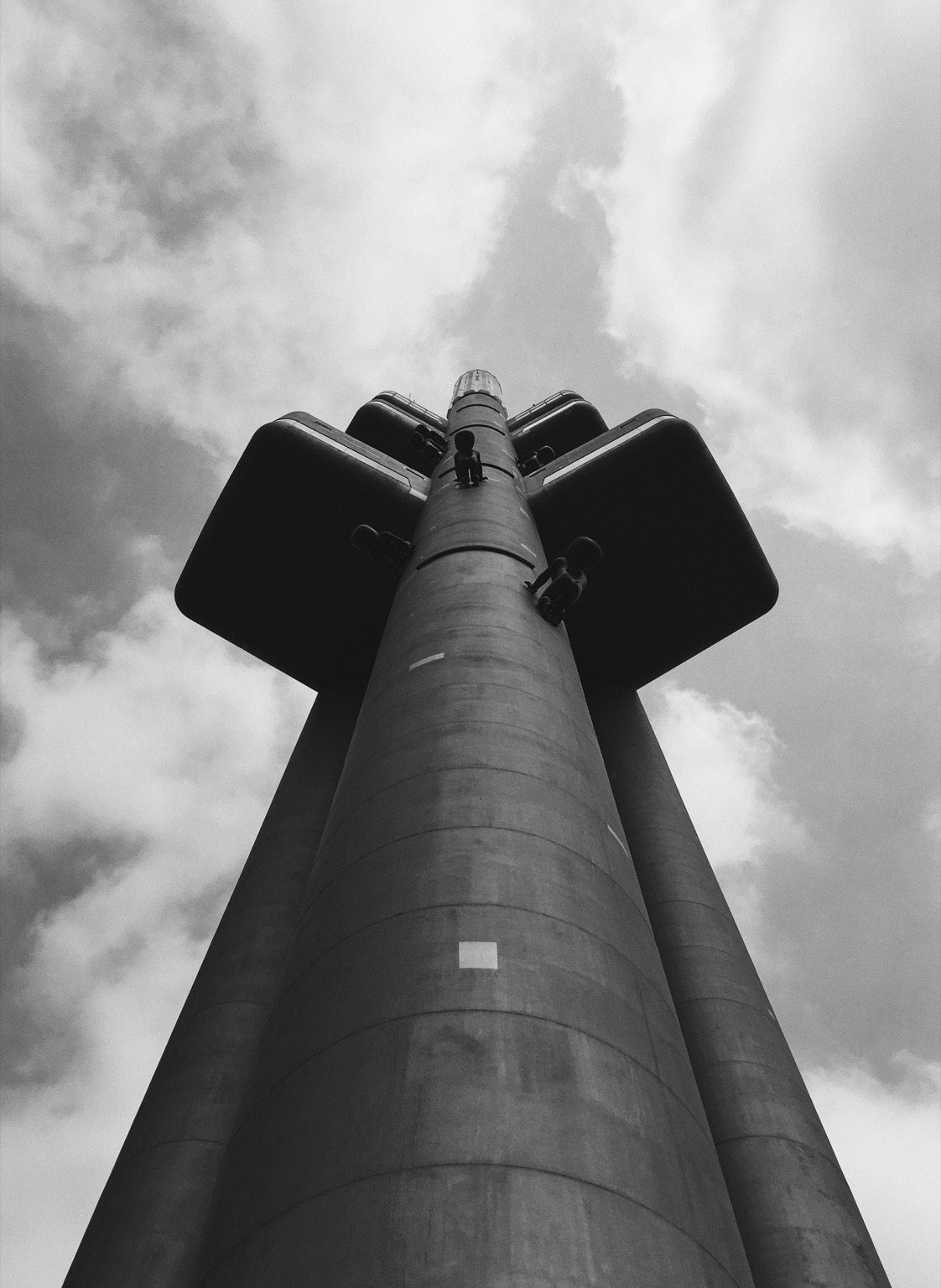 Black and white photography of Prague TV Tower, taken from the ground and looking at the top of the tower.