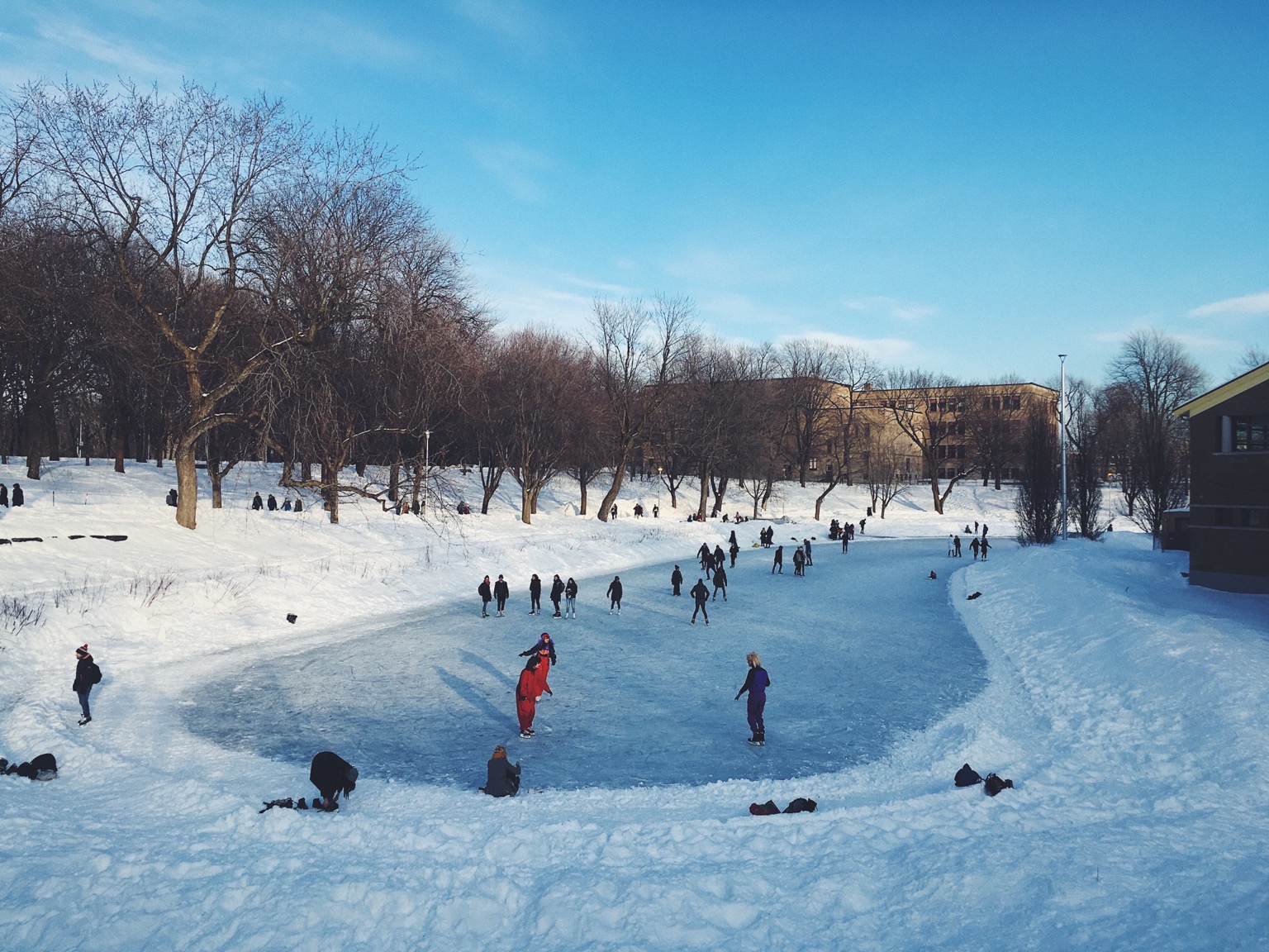 People ice skating on the lake of Parc La Fontaine in Montréal on a winter day.